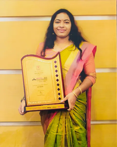 Athira Anoop, founder of Adhi's Bake House, holding the Metro Food Awards 2023 Best Bakers trophy